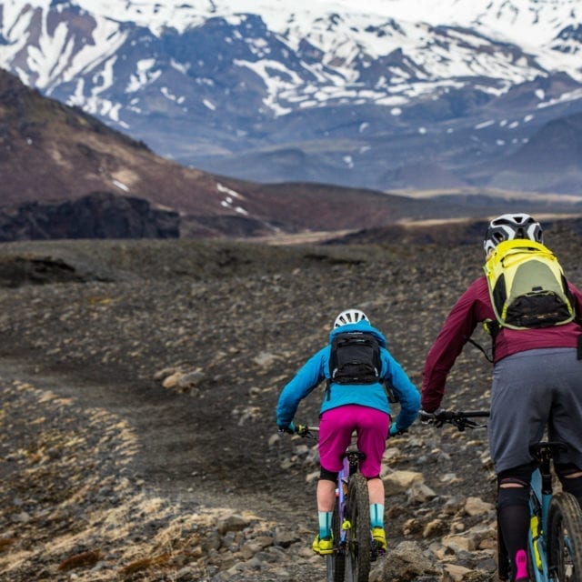 Two riders Biking towards snow covered mountains